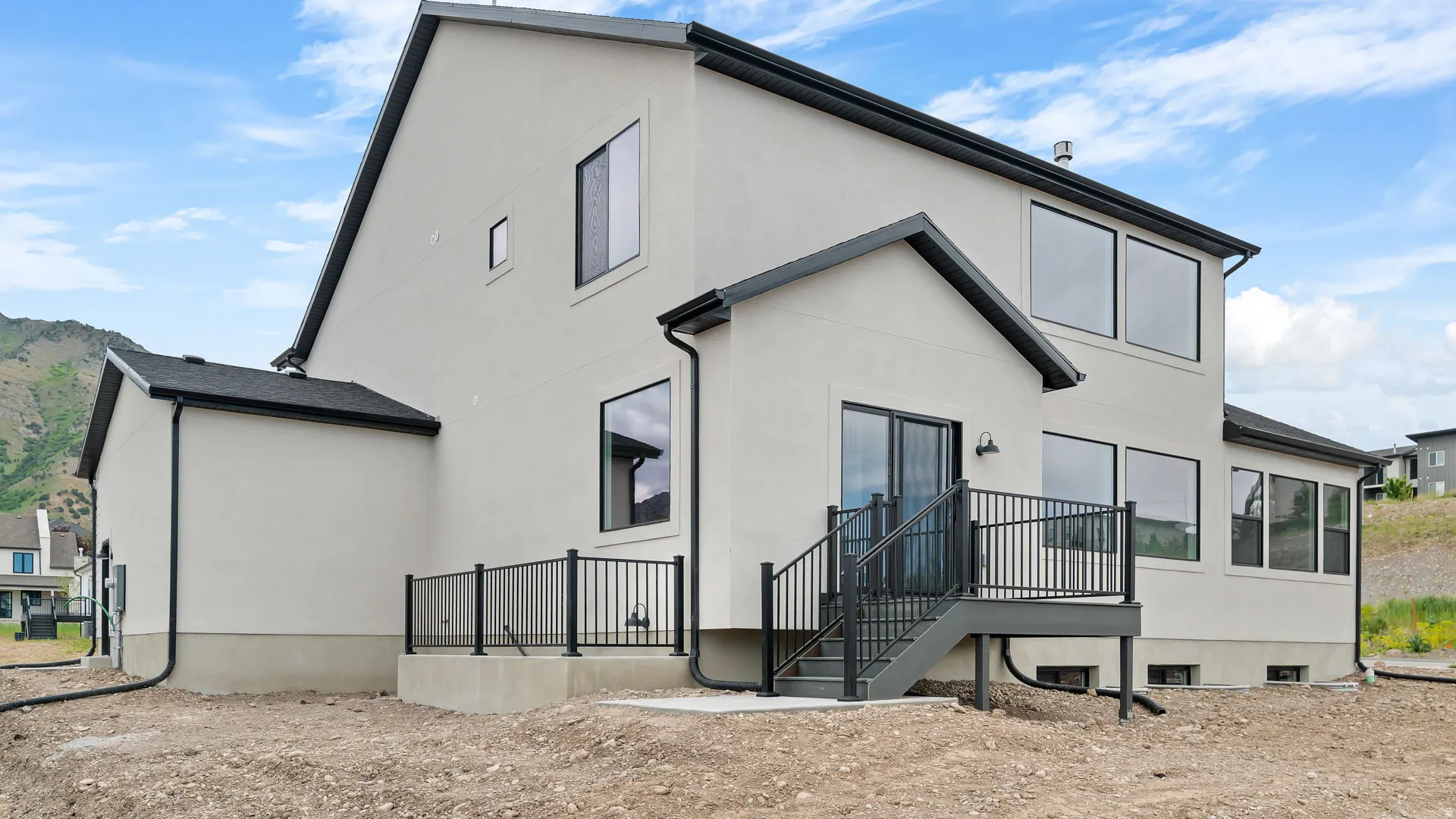 Contemporary residence featuring light-colored stucco siding, dark-framed windows, and a multi-level deck with black railings