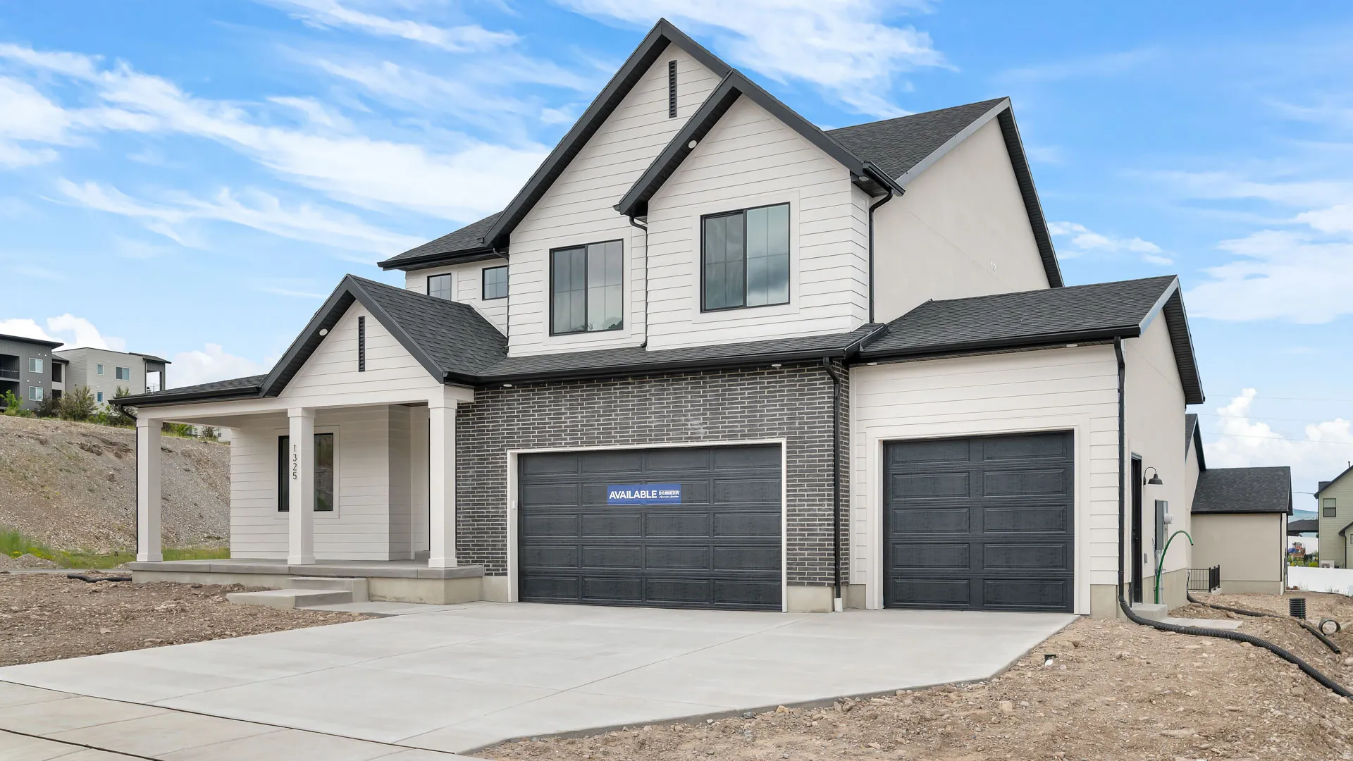 Modern two-story residence with a multi-material exterior featuring white siding and dark brick accents