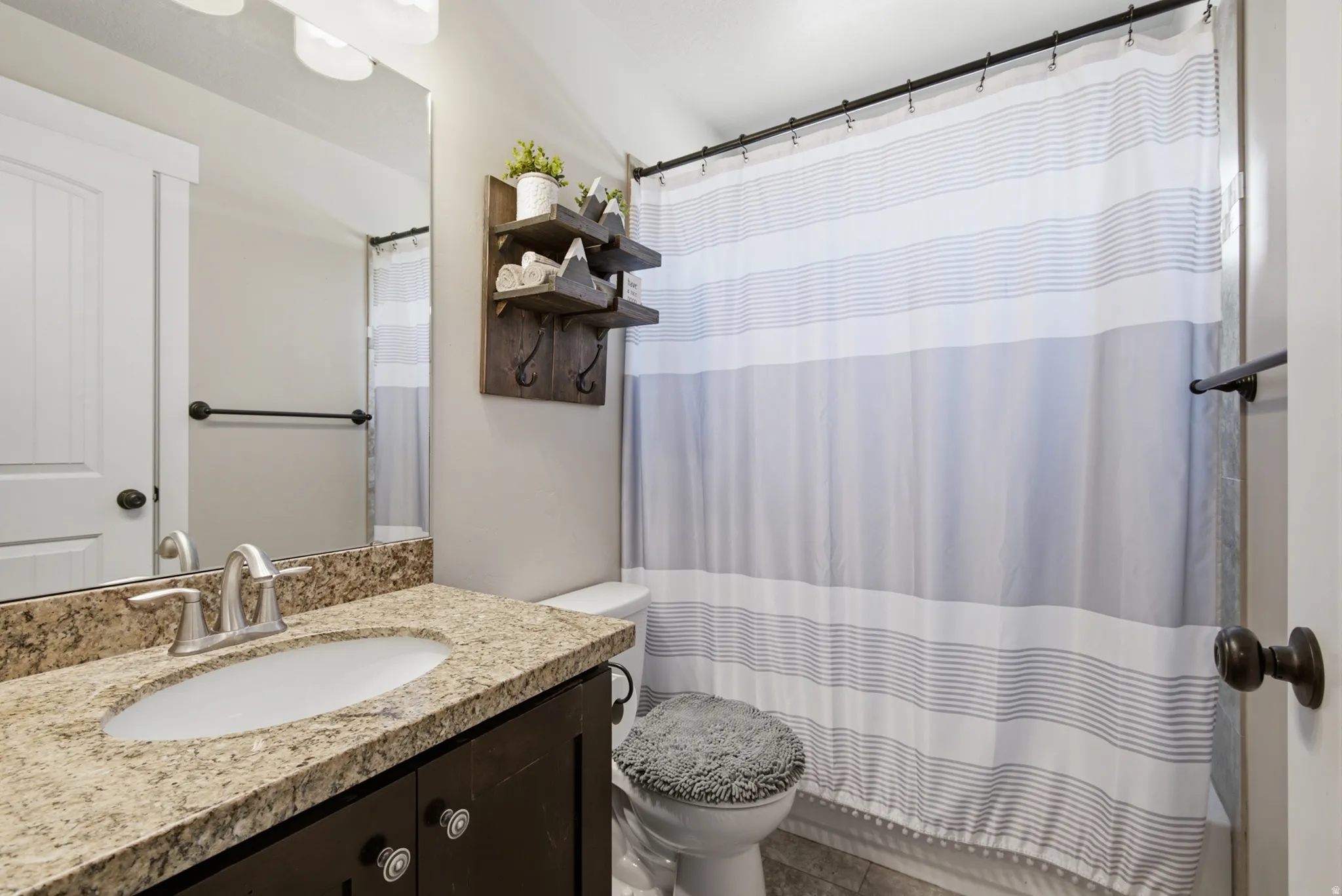 Bathroom featuring a vanity with a light-colored stone countertop, an undermount sink, and a dark wood-finish cabinet