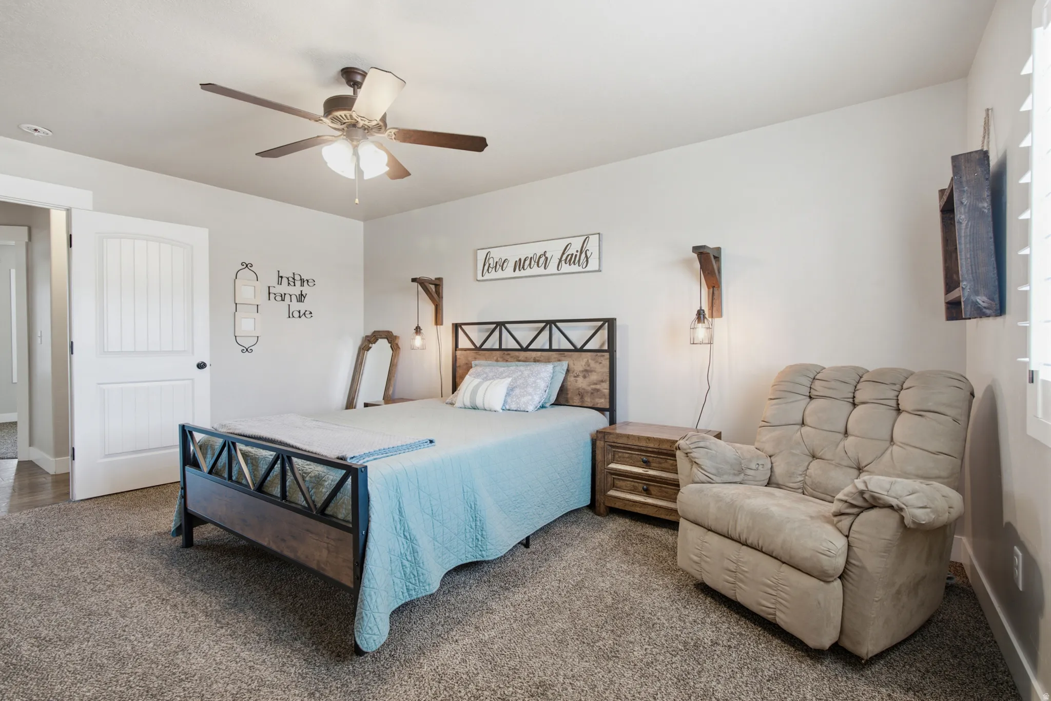 Carpeted room featuring a ceiling fan with integrated lighting, a paneled interior door, and a window with white louvered shutters