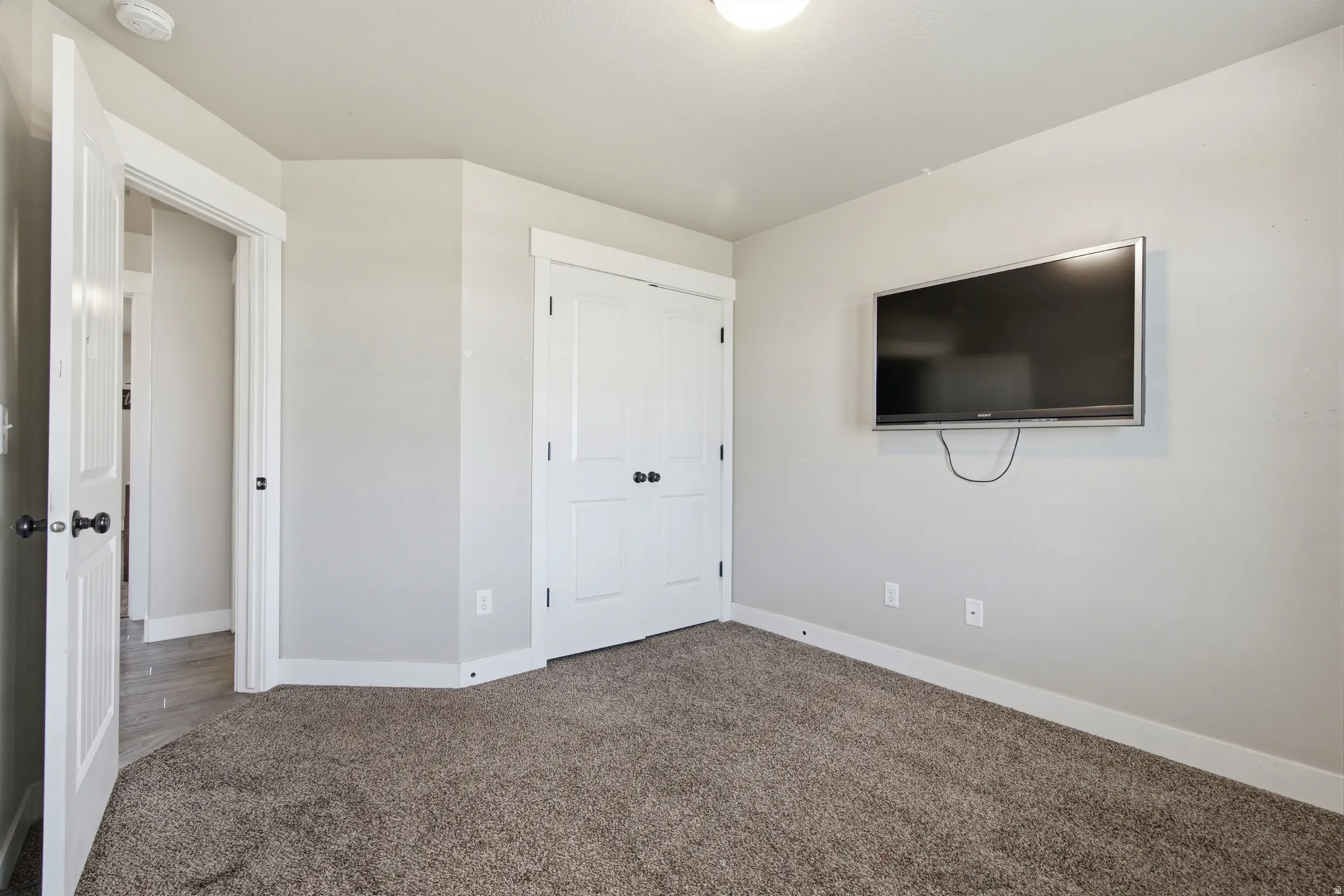 Carpeted room featuring light gray walls, white trim, and a ceiling-mounted light fixture