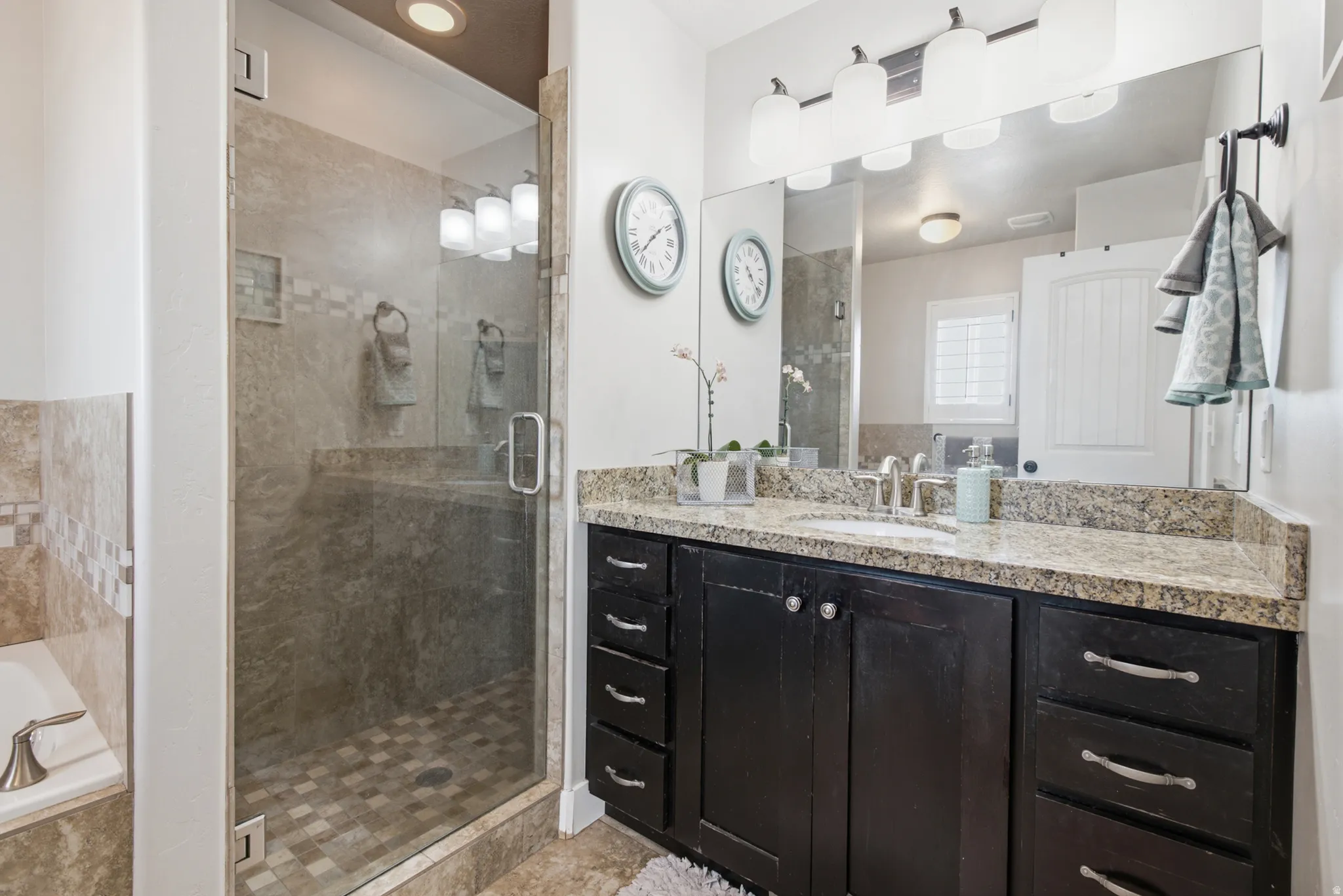 Bathroom featuring a dark wood-finish vanity with granite countertop, an undermount sink, and a framed mirror