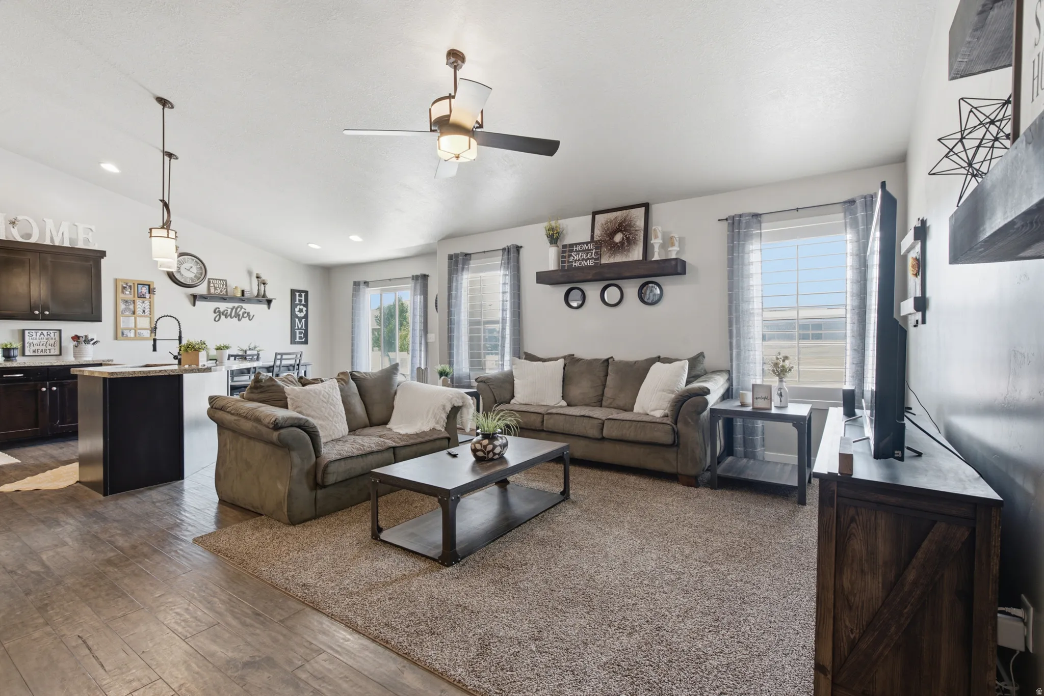 Open-concept living area featuring wood-finish flooring, recessed lighting, and a ceiling fan