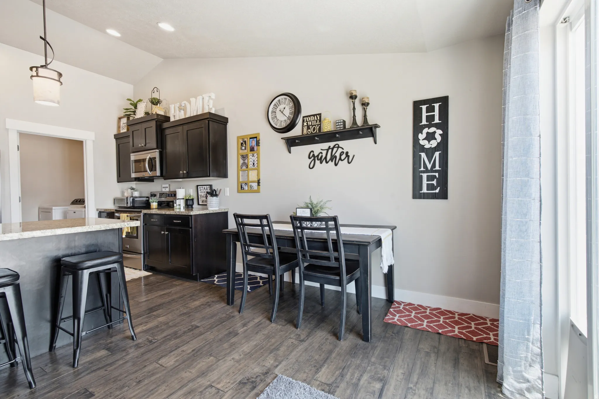 Open-concept kitchen and dining area featuring wood-finish flooring, dark cabinetry, and a light-toned countertop