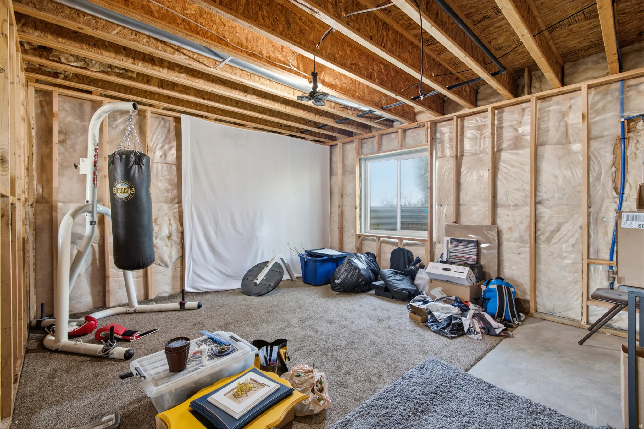 Unfinished basement space featuring exposed wooden framing, visible insulation, and a single window