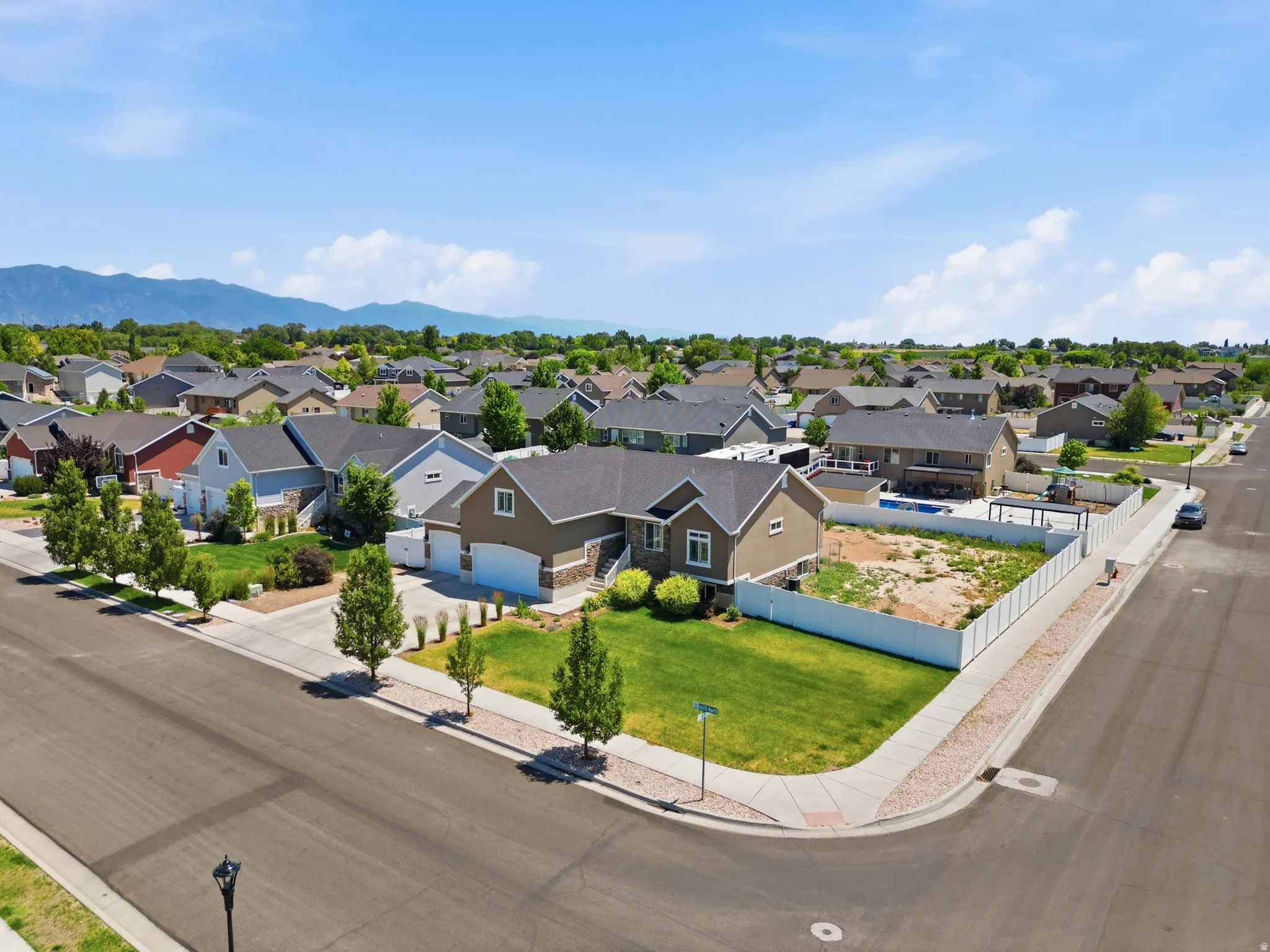 Corner lot residence featuring a two-car garage, established front landscaping, and a fenced side yard