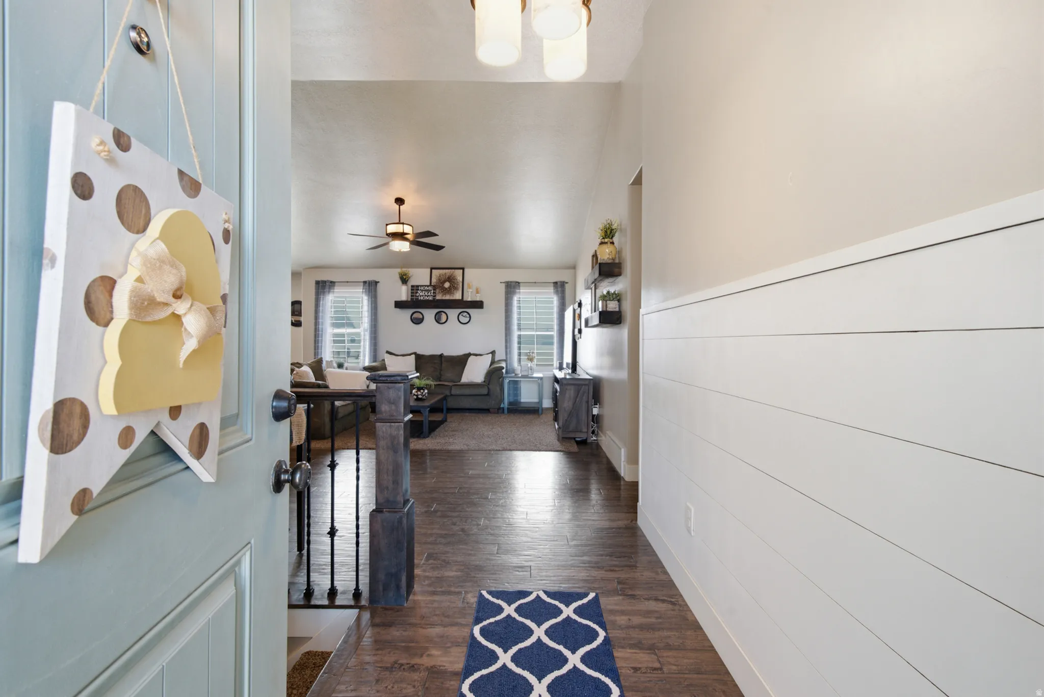 Inviting entryway featuring a light blue door, shiplap accent wall, wood-finish flooring, and a ceiling light fixture