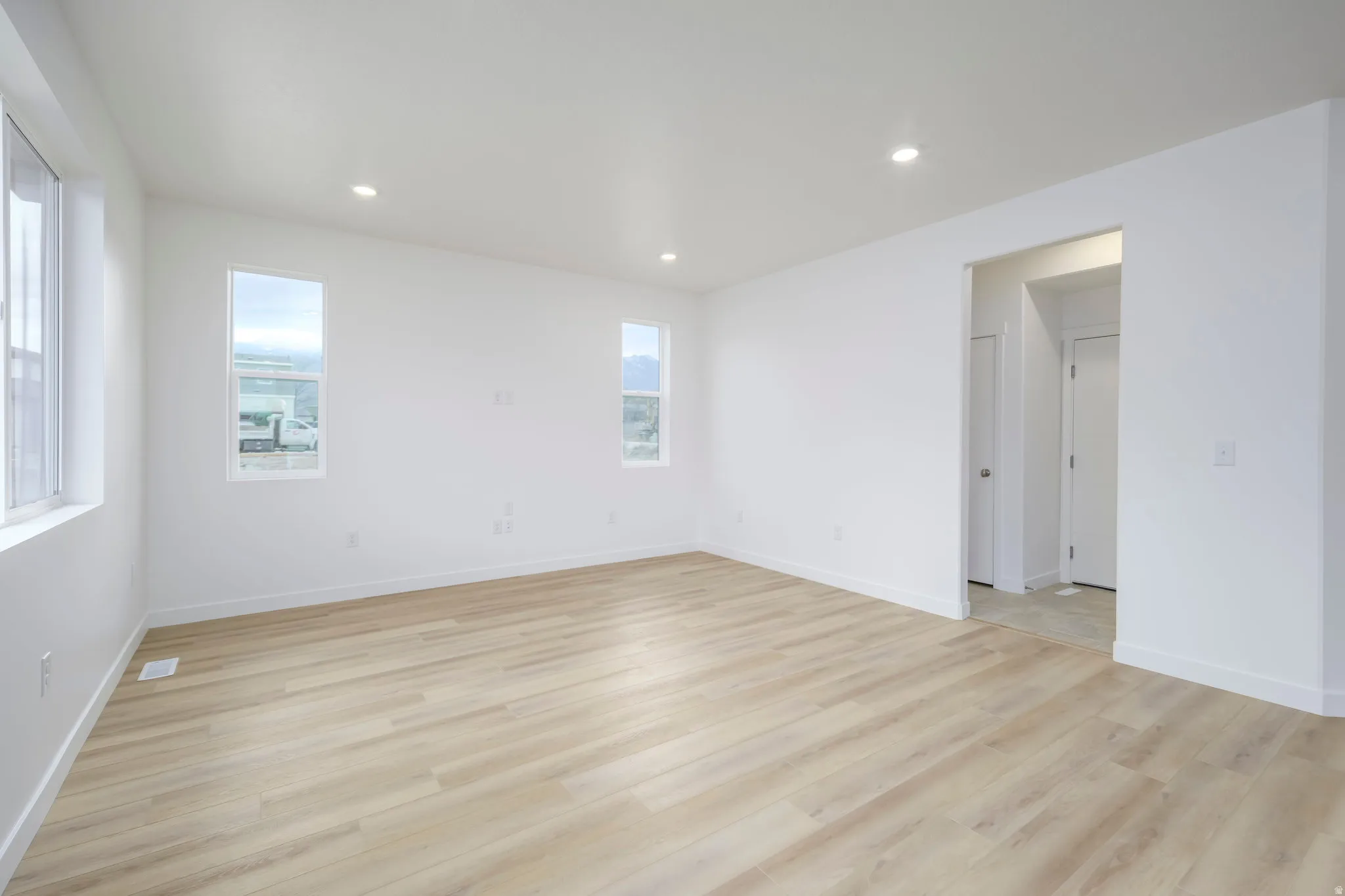 Bright room featuring wood-finish flooring, recessed lighting, and crisp white walls