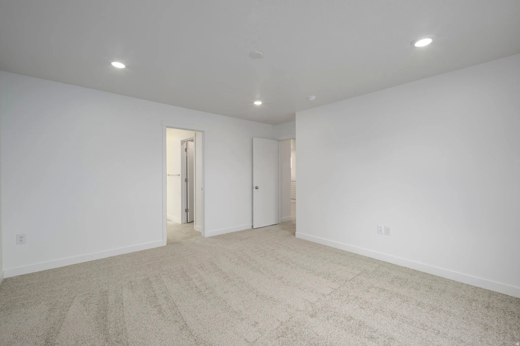 Spacious room featuring neutral carpeting, white walls, and recessed lighting