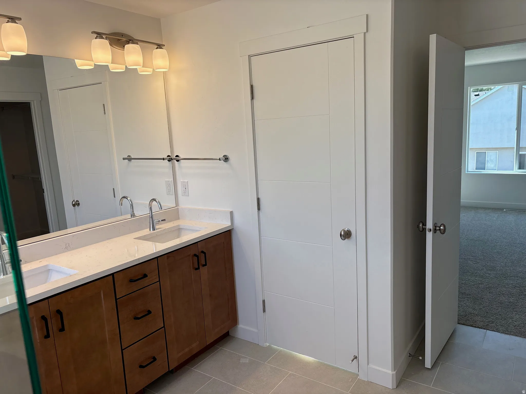 Bathroom featuring a dual vanity with light wood-finish cabinetry, white countertop, and integrated sinks