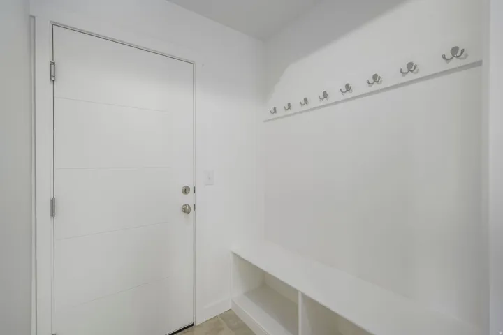 Entryway featuring a modern panel door with horizontal grooves, brushed nickel hardware, and a built-in white bench with open shelving