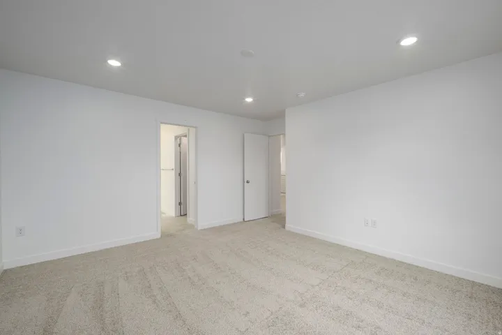 Spacious room featuring neutral carpeting, white walls, and recessed lighting