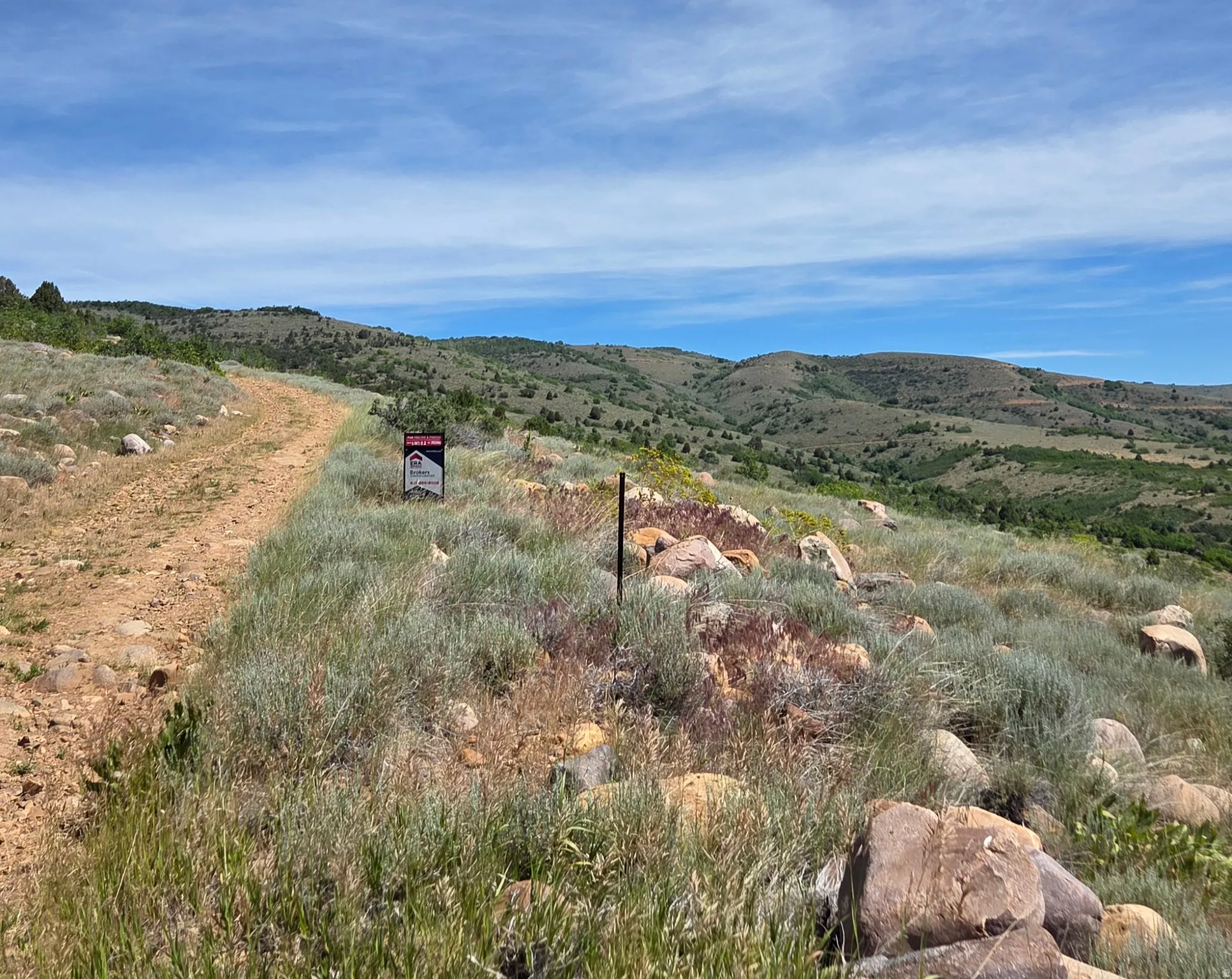 Expansive undeveloped land featuring natural rock formations and a dirt road
