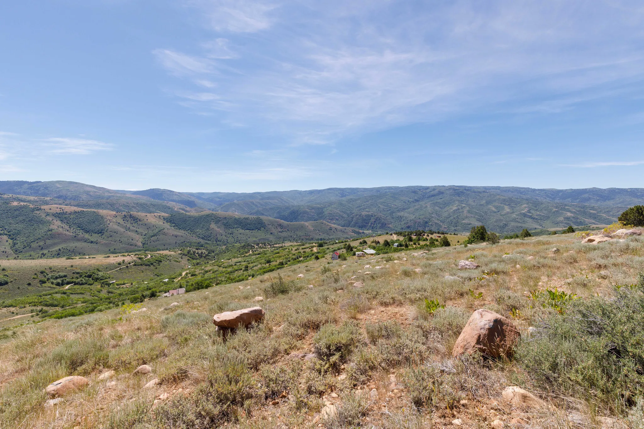 Expansive mountain landscape featuring varied terrain and distant green hills under a clear sky