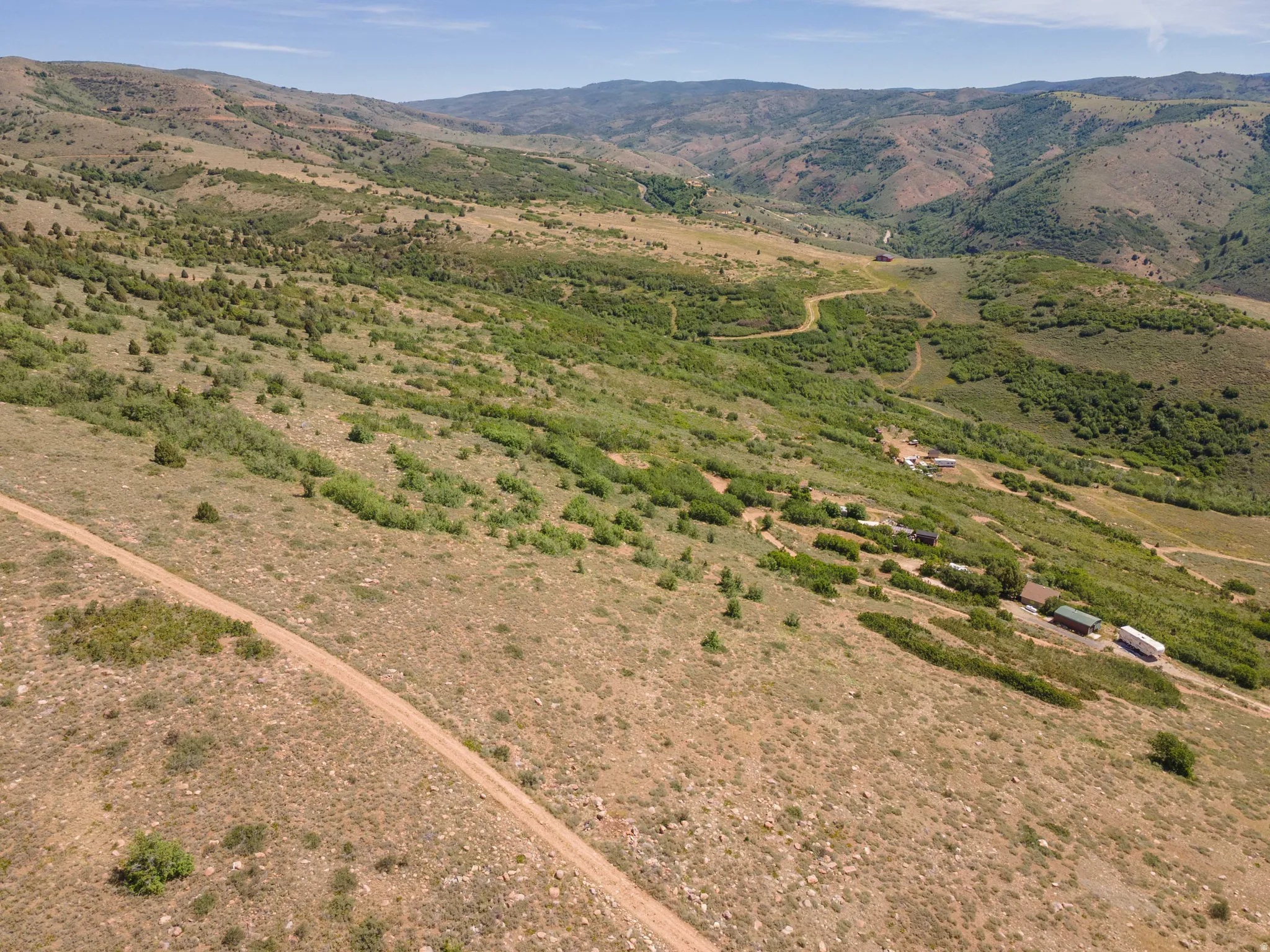 Expansive acreage featuring a dirt road, varied terrain, and distant mountainous topography