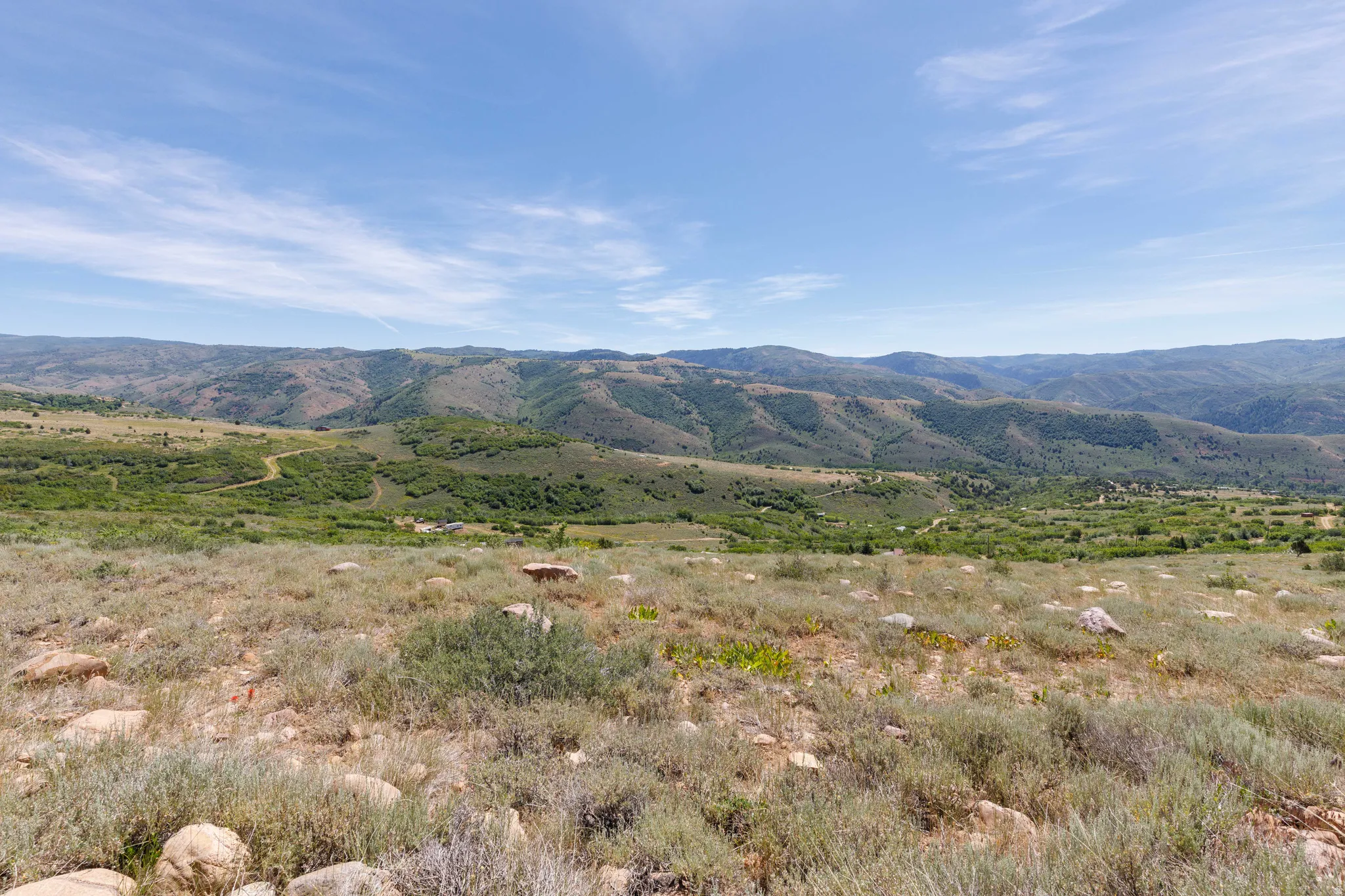 Expansive natural landscape with rolling hills and distant mountains under a clear sky