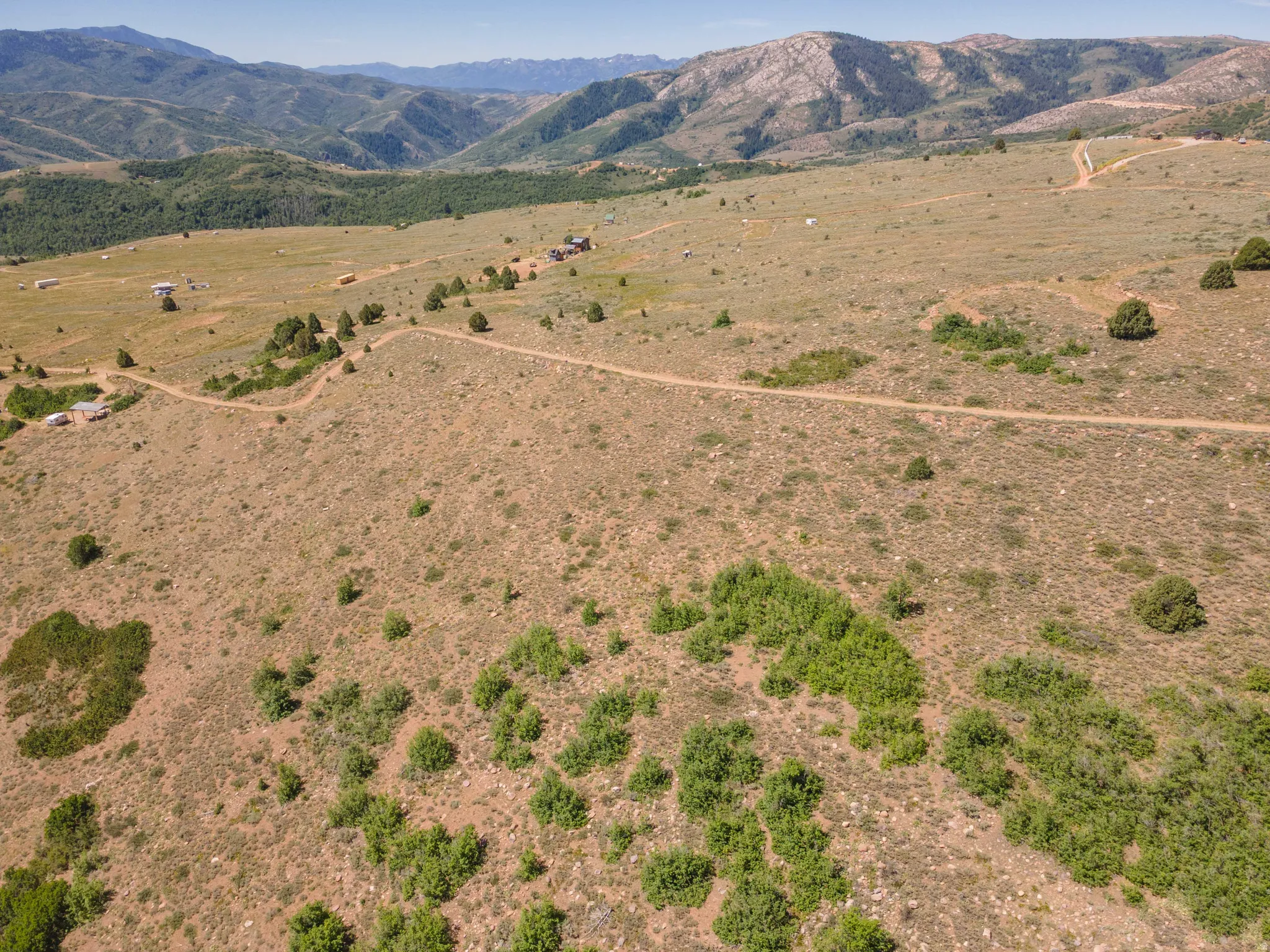 Expansive mountain acreage featuring natural terrain, mature scrub brush, and distant mountain ranges