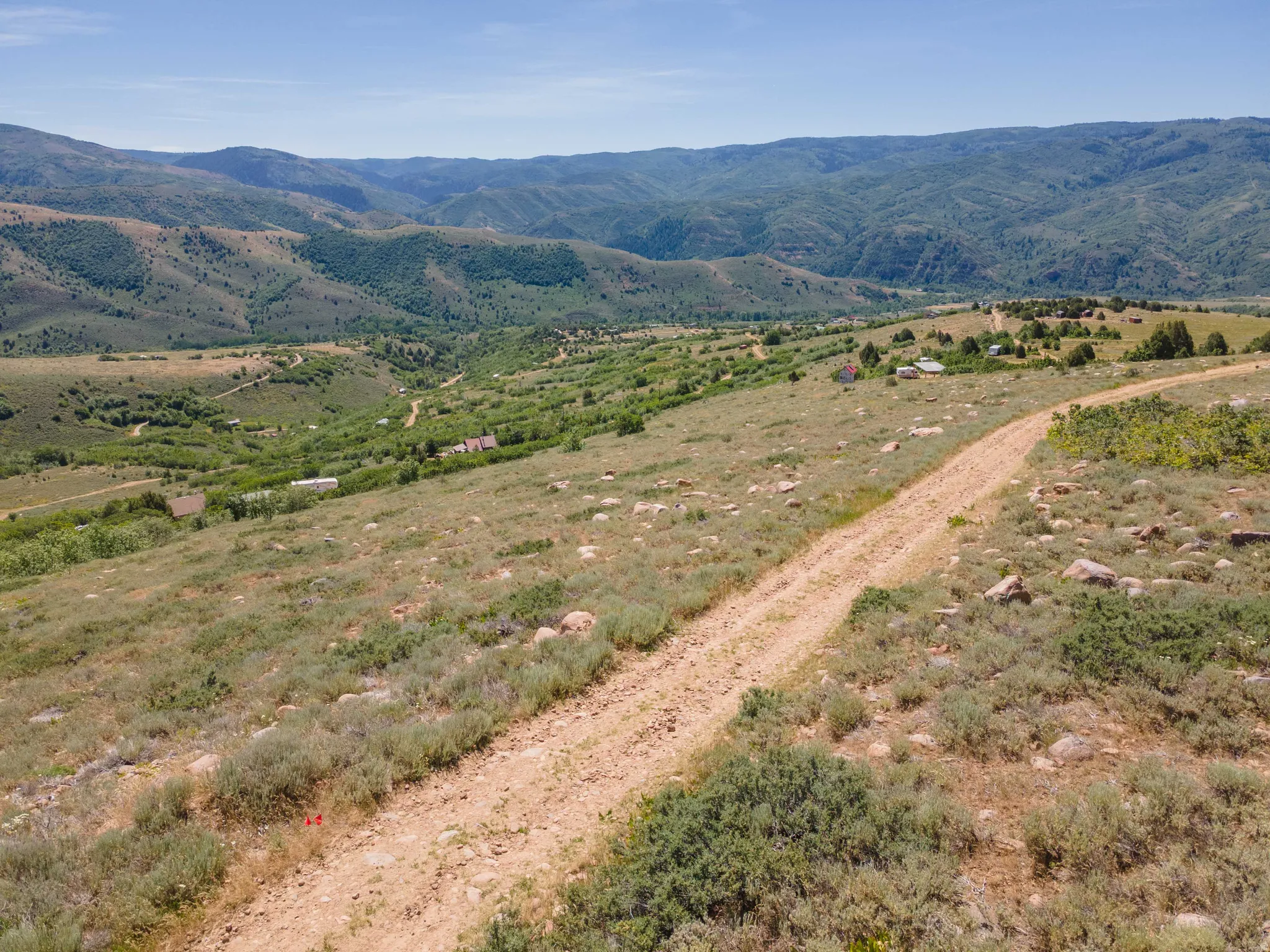 Expansive mountainous terrain featuring scattered shrubbery and a dirt path