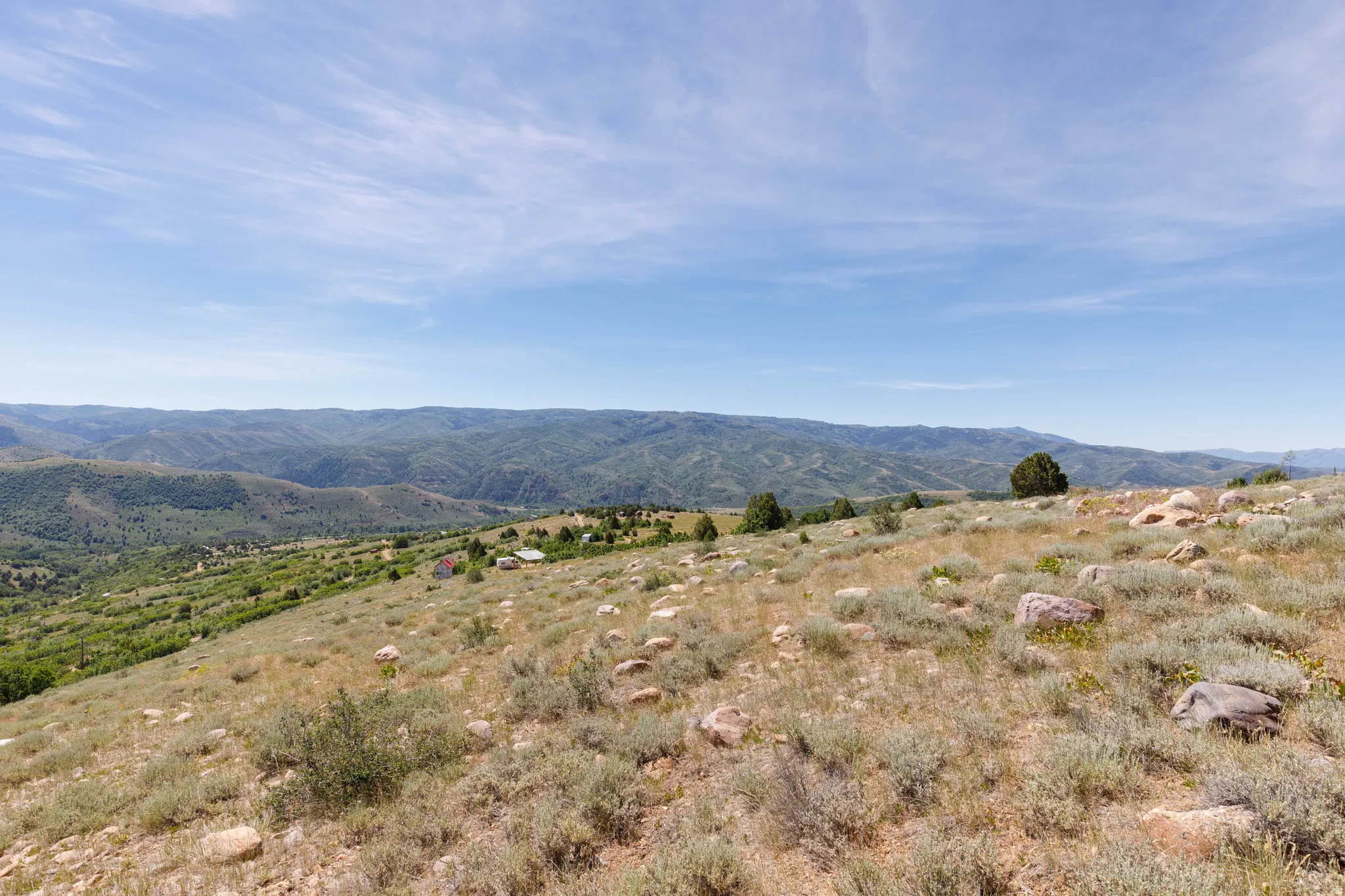 Expansive hillside landscape featuring distant mountainous terrain under a clear sky