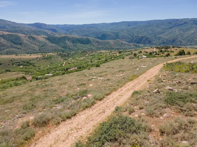 Expansive mountainous terrain featuring scattered shrubbery and a dirt path