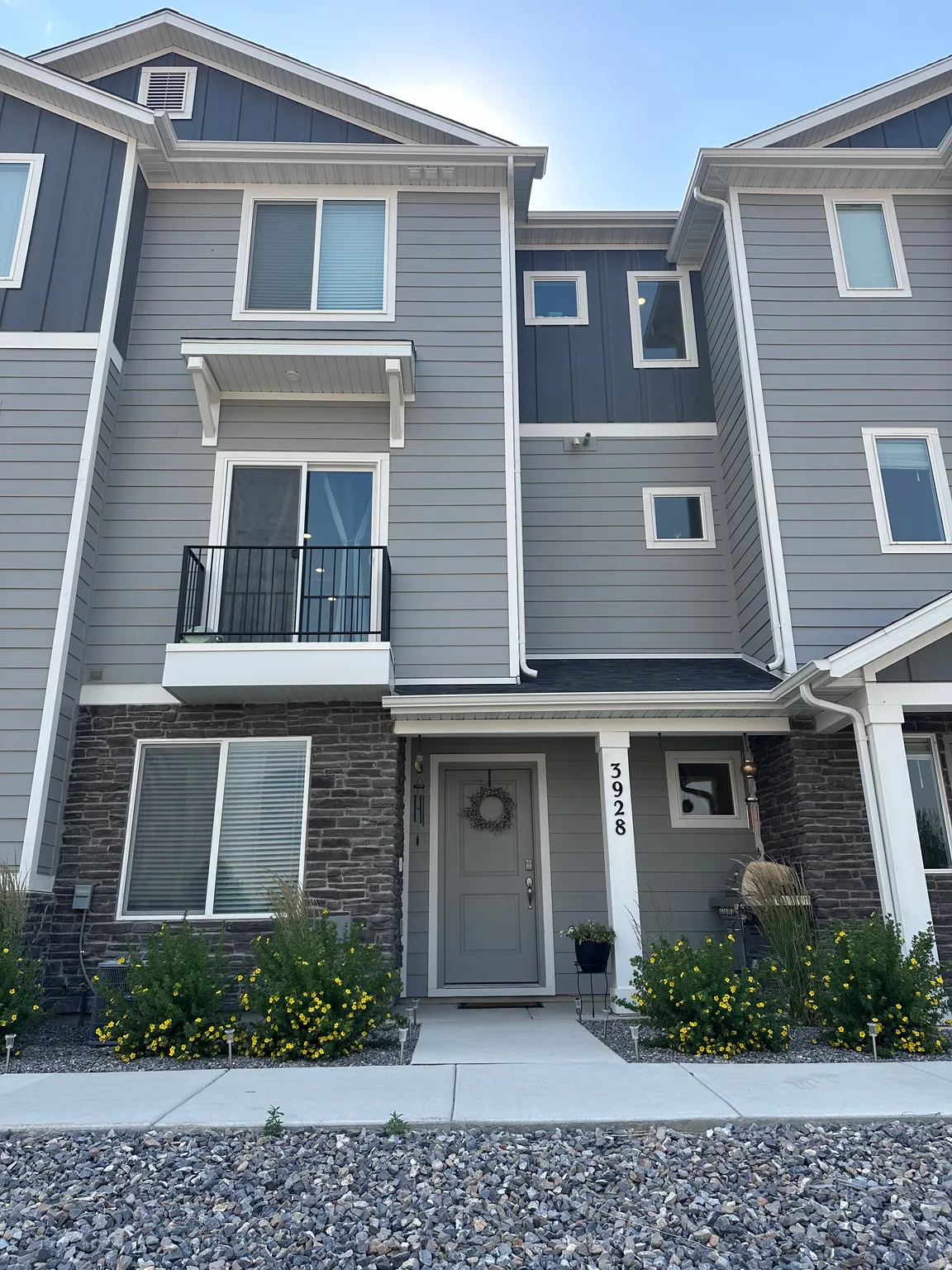 Multi-story townhome with a mixed material exterior featuring stone veneer and horizontal siding
