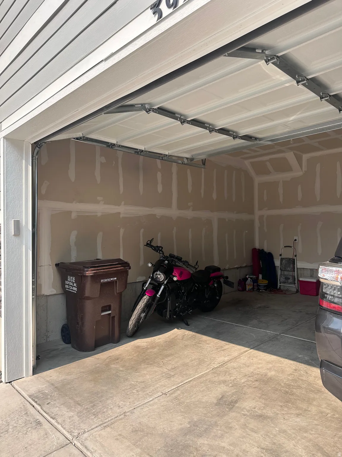 Attached garage featuring a concrete floor and unfinished drywall