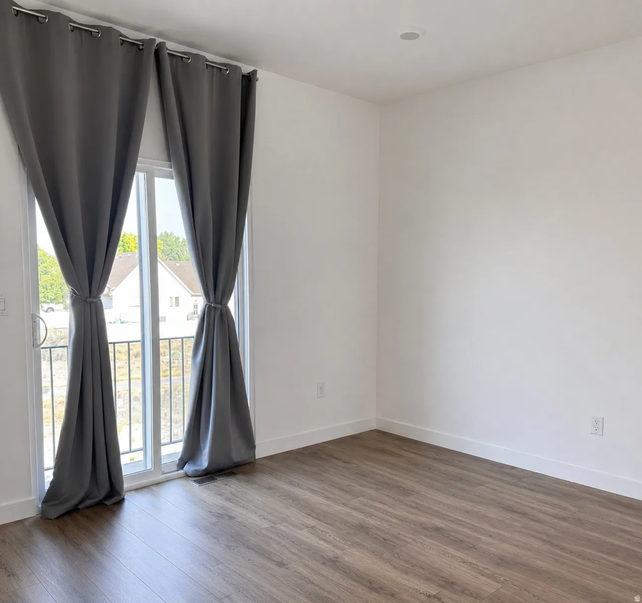 Spacious room featuring wood-finish flooring, crisp white walls, and a recessed ceiling light