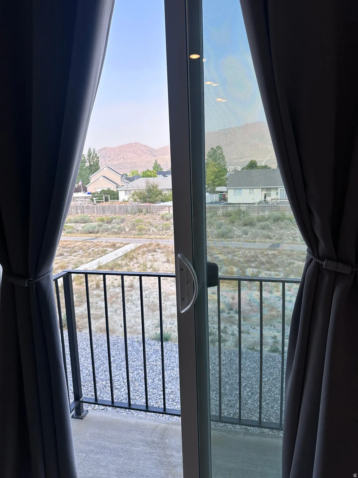 Sliding glass door with integrated screen, leading to an outdoor balcony with black metal railings