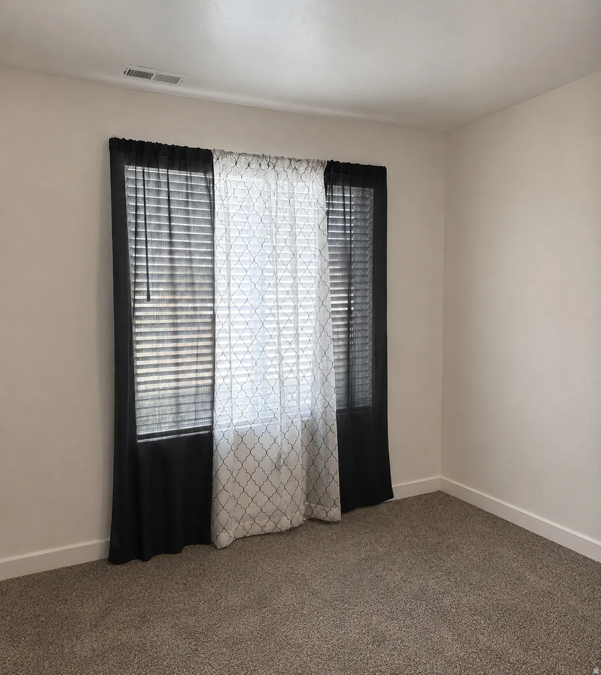 Room featuring light neutral wall paint, white trim, and textured carpet flooring