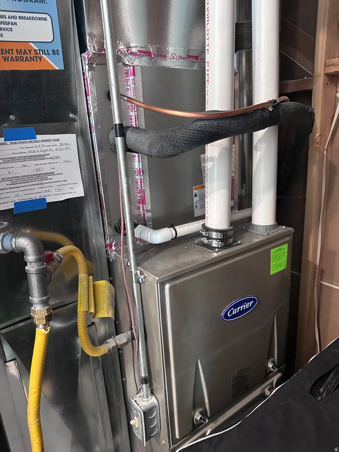 Carrier branded HVAC system with exposed ductwork, insulated copper piping, and a flexible gas line connection