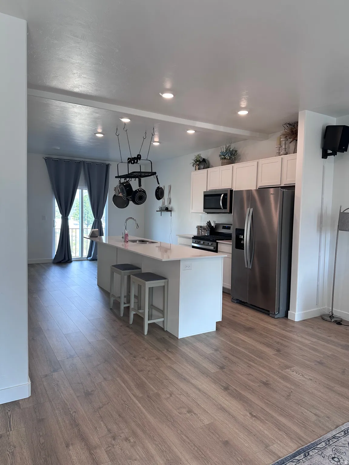 Open-concept kitchen featuring an oversized island with seating, stainless steel appliances, white cabinetry, and recessed lighting