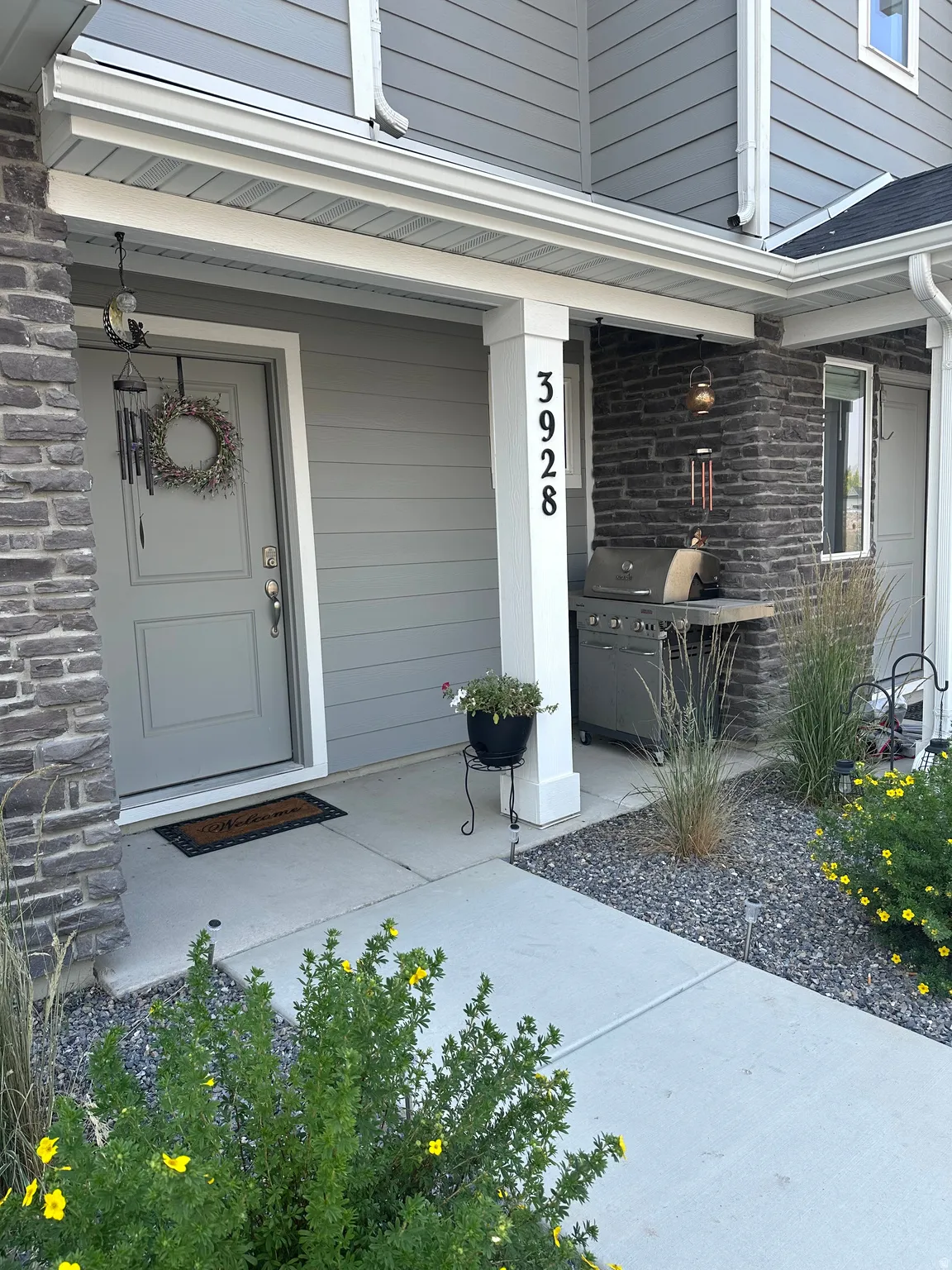 Inviting entryway featuring gray horizontal siding and stone accents
