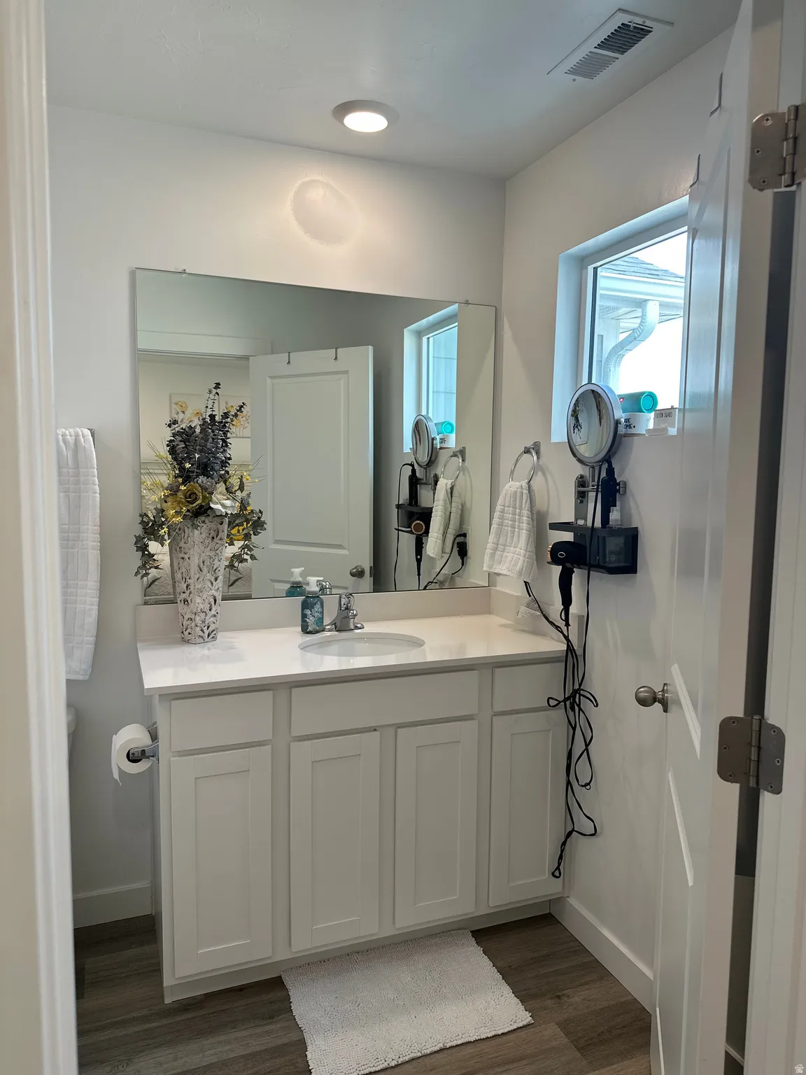 White vanity with a single basin, light-toned countertop, and undermount sink