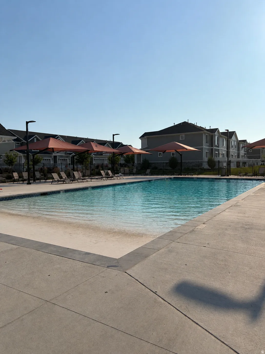 Expansive swimming pool featuring a zero-entry design and surrounding concrete decking