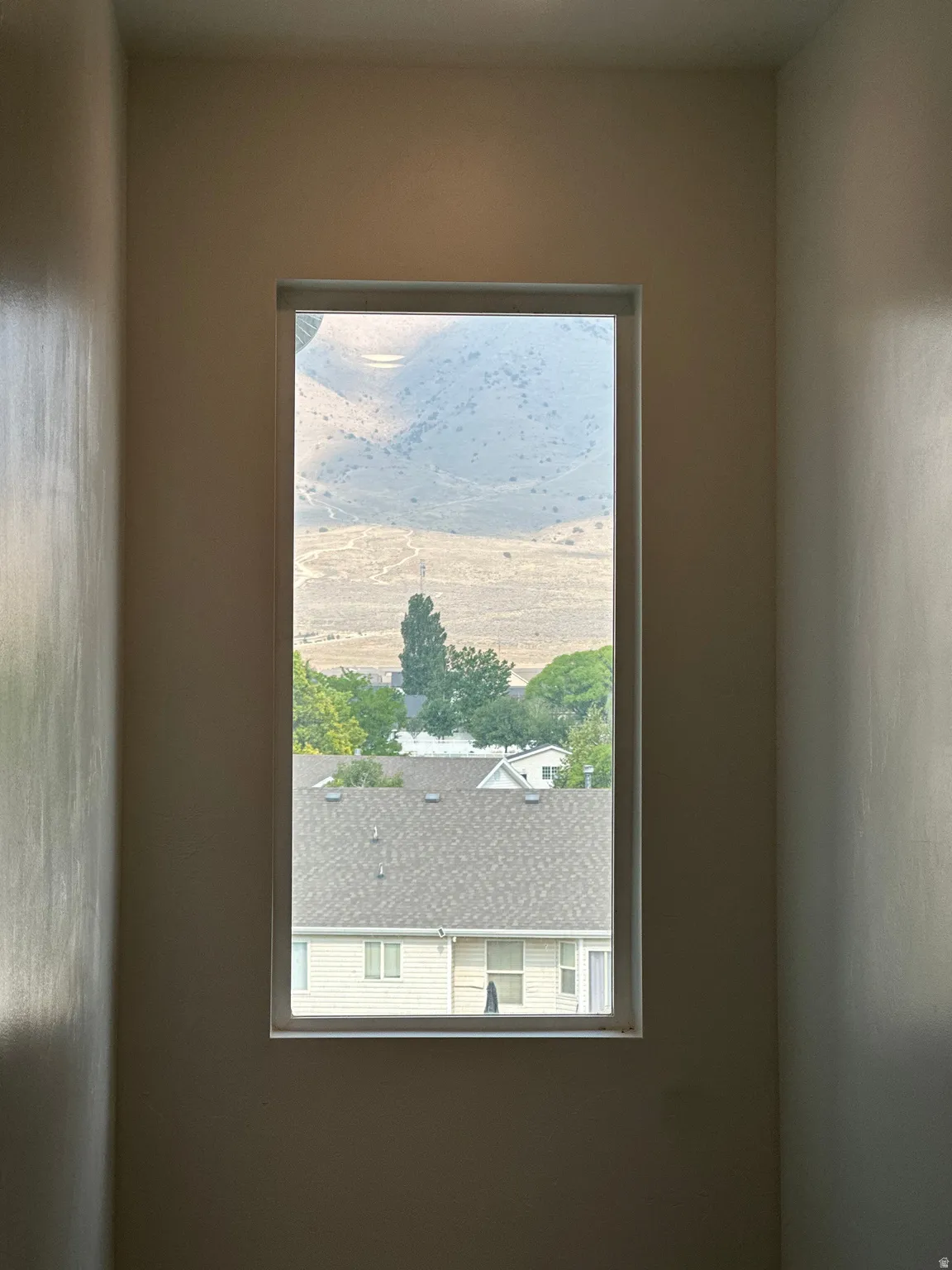 Window framing distant mountains and surrounding rooftops