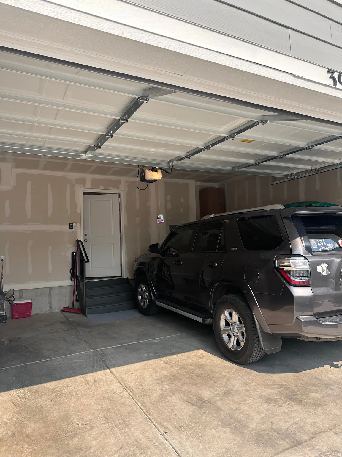 Attached garage featuring concrete flooring, an interior access door, and a multi-step entry with handrail
