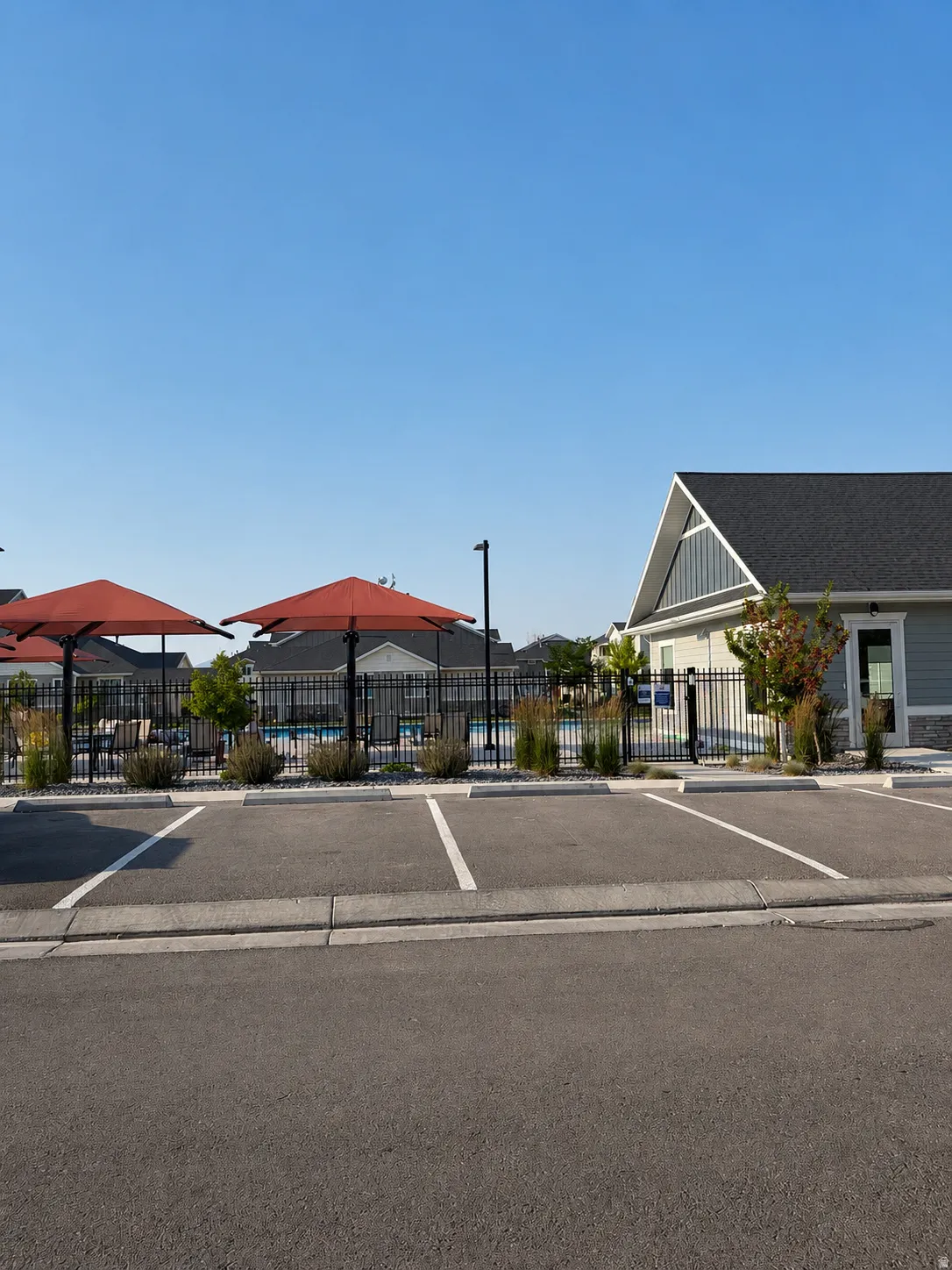 Community parking lot with striped spaces, adjacent to a recreation building featuring a gable roof and siding