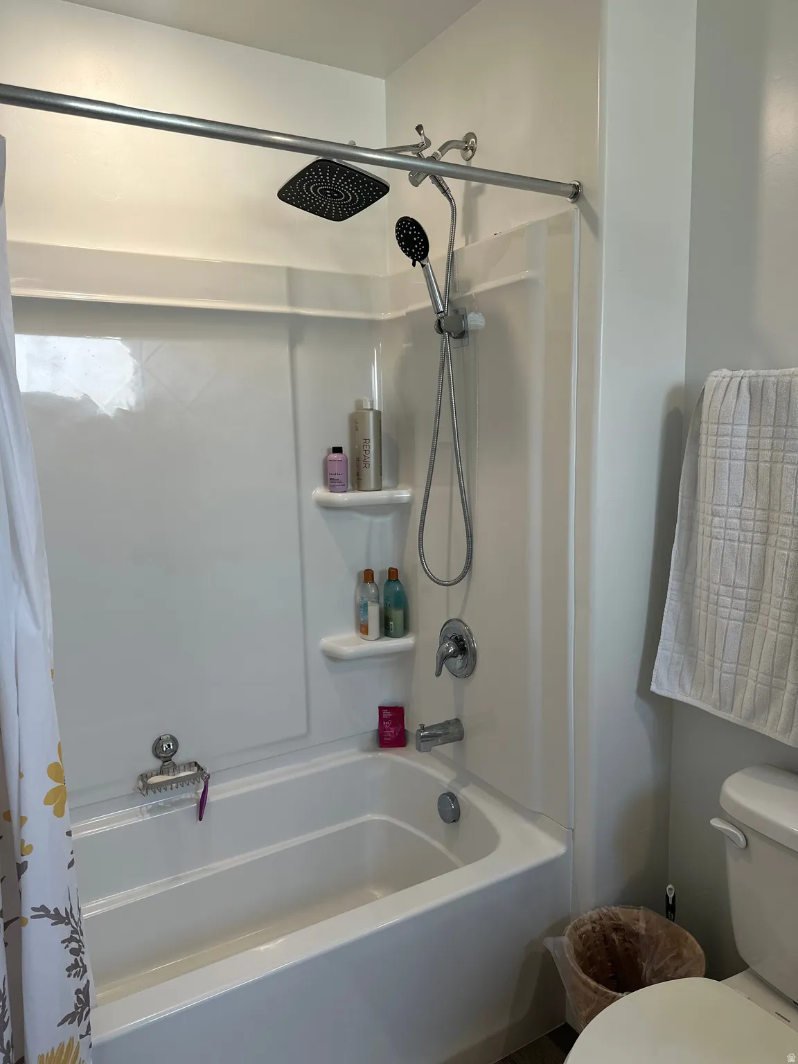 Bathtub and shower combination featuring a dual showerhead system with a square rainfall showerhead and a handheld shower attachment