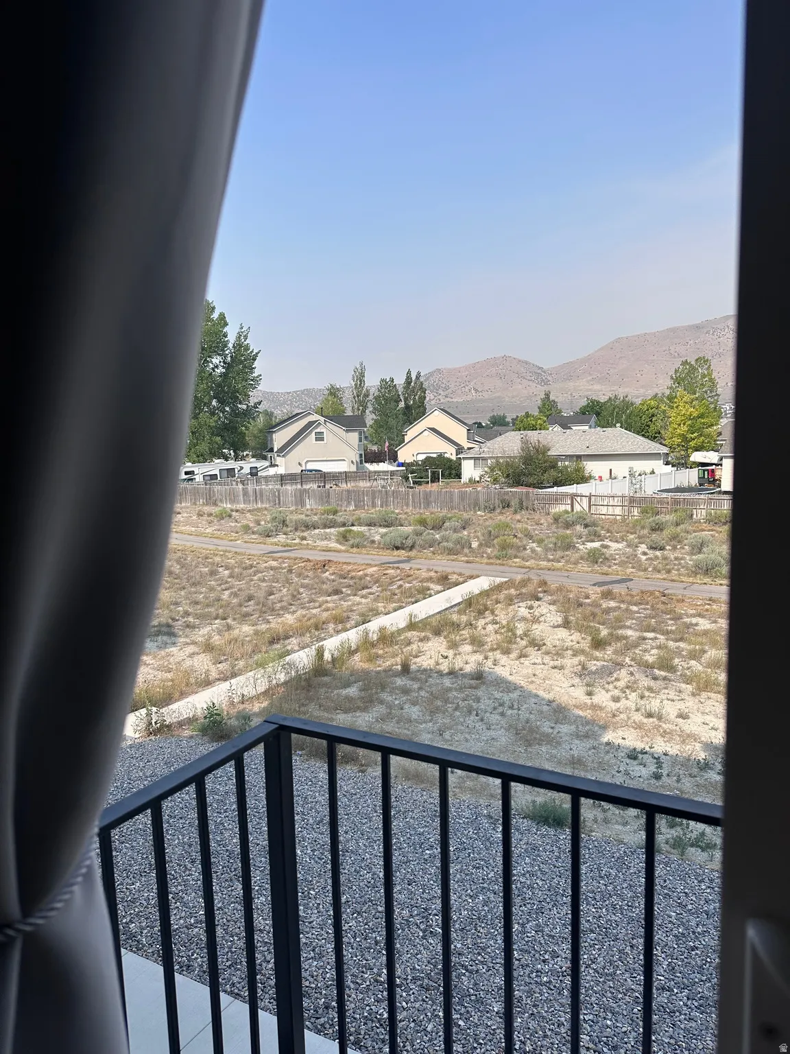 Balcony with black metal railing overlooking a natural landscape with distant mountains