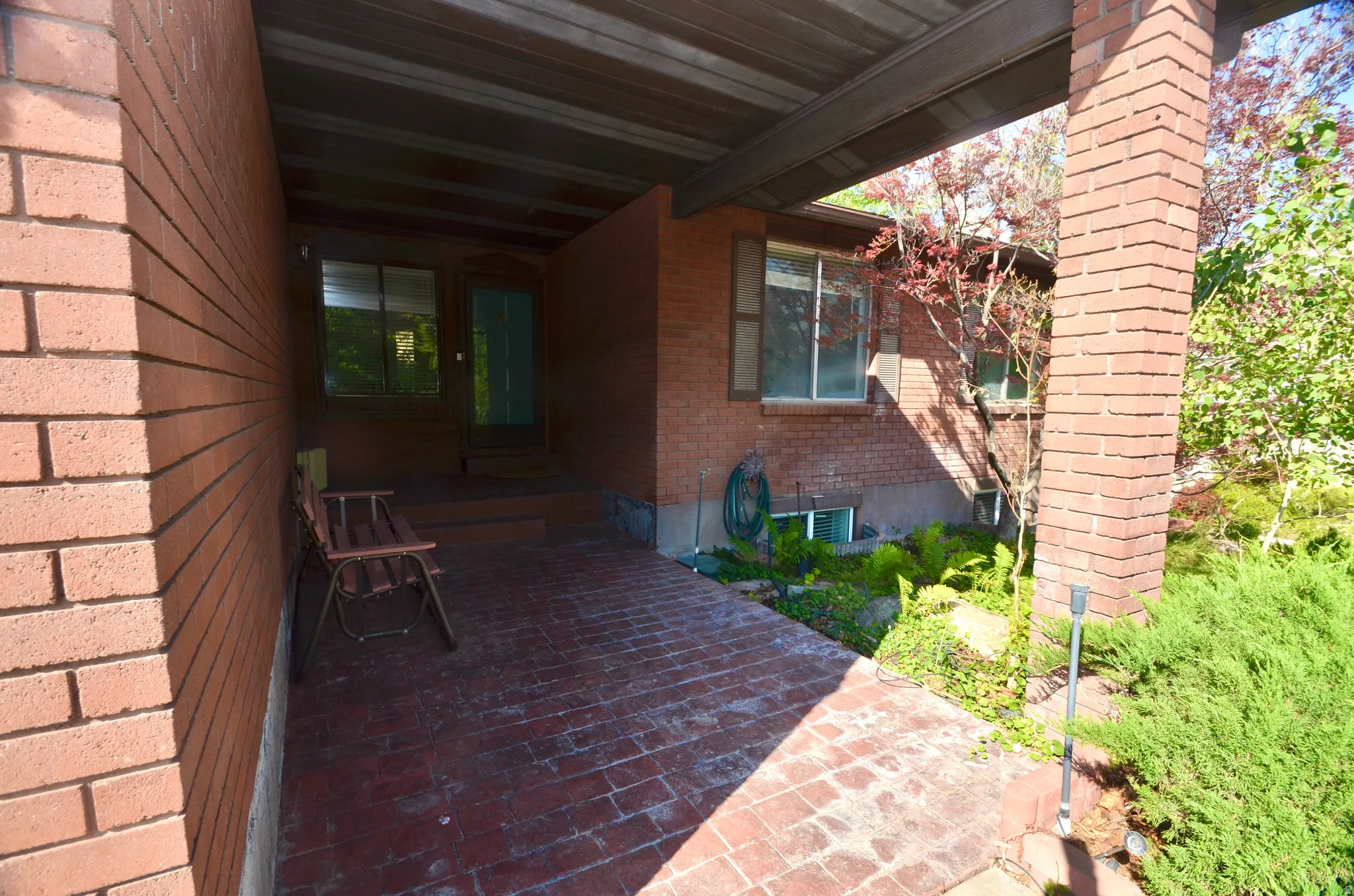 Brick exterior with an overhead porch structure featuring a wood-finish ceiling