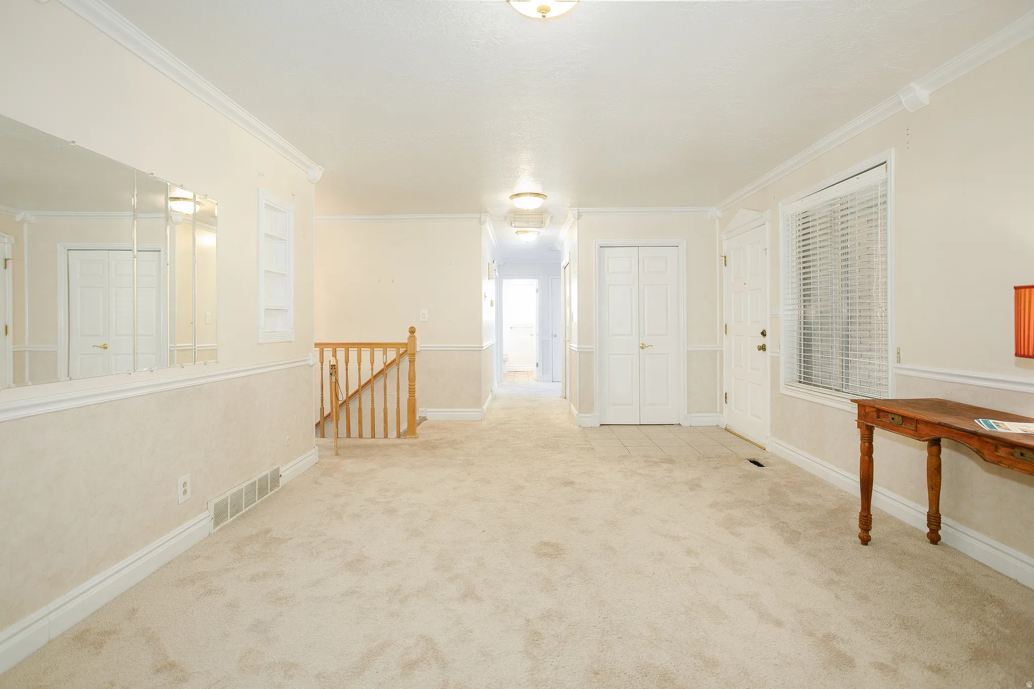 Inviting entry featuring neutral-toned carpeting, white baseboards, and crown molding