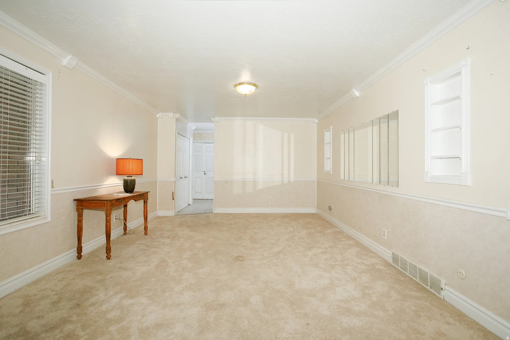 Spacious room featuring neutral carpet flooring and light-toned walls with chair rail molding