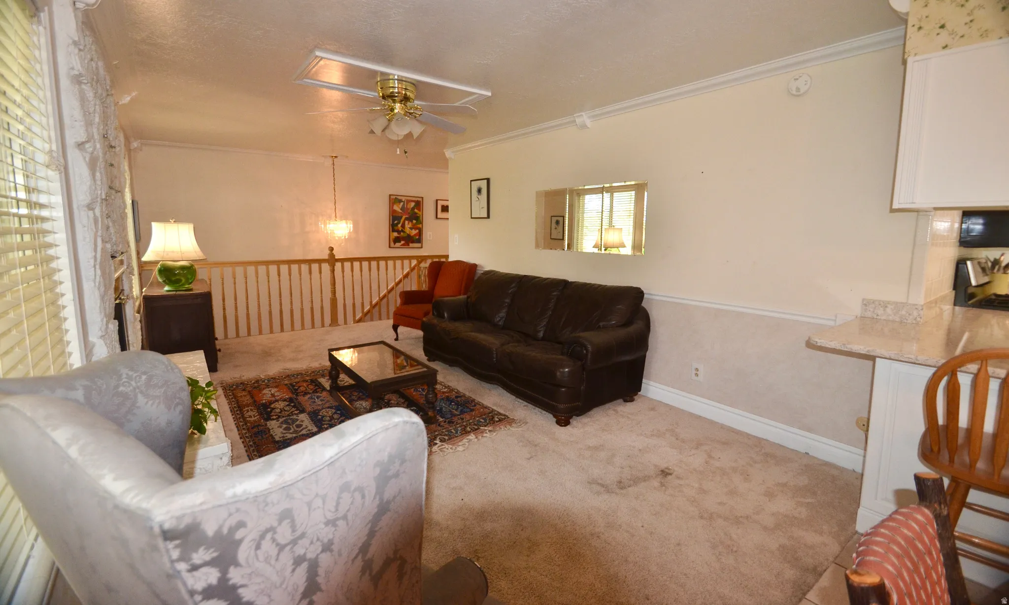 Living area with carpeted flooring, a ceiling fan with integrated lighting, and crown molding