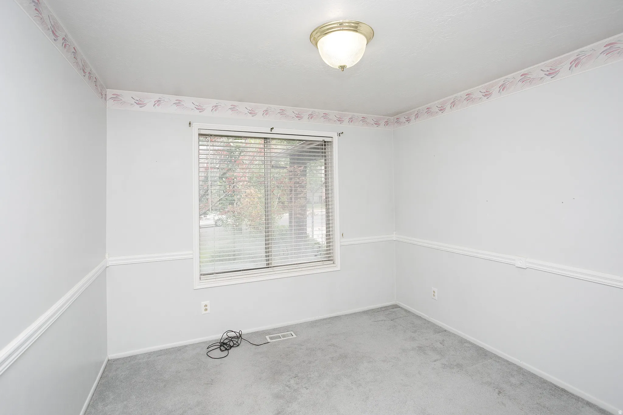 Room featuring a single window with blinds, wall molding, and a decorative border