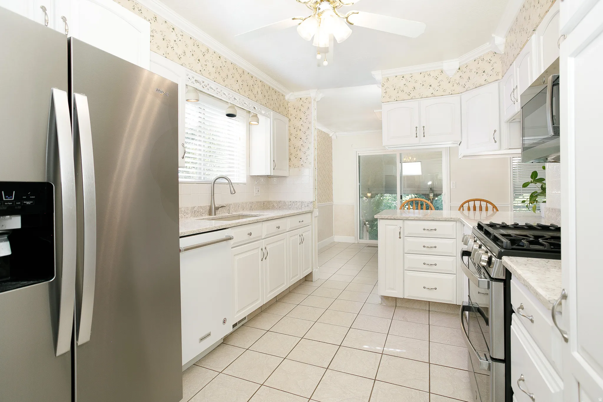 Kitchen featuring white cabinetry, light-toned countertop surfaces, stainless steel appliances, and white tile flooring