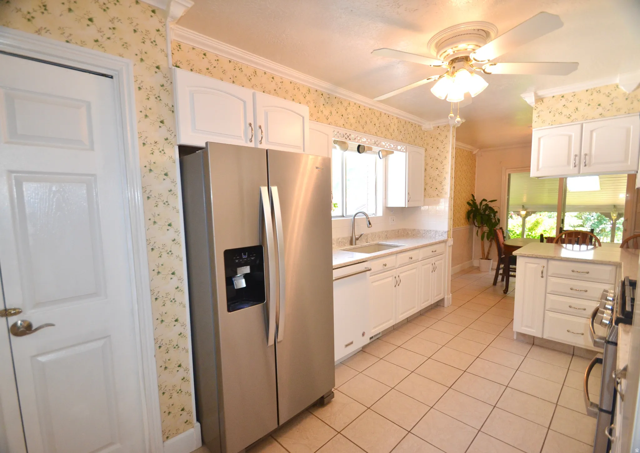 Kitchen featuring white cabinetry, light-toned countertops, a stainless steel refrigerator, and tiled flooring