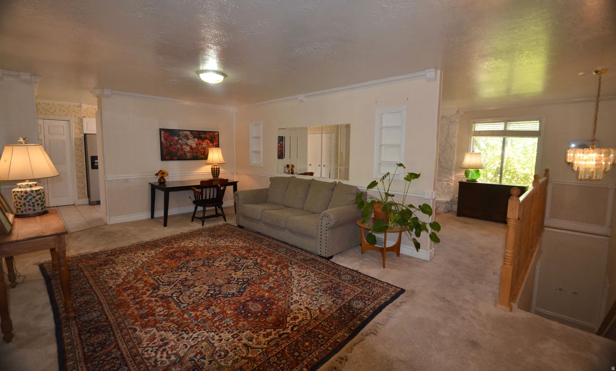 Carpeted living area featuring recessed shelving, chair rail molding, and a built-in mirror