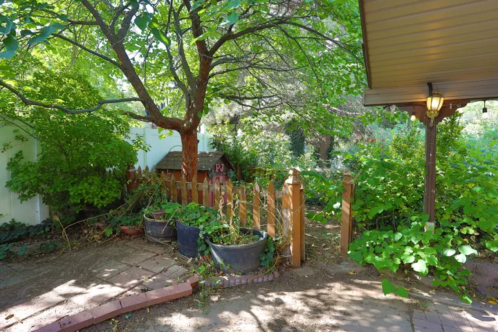 Patio area featuring brick paving, mature tree, and lush greenery