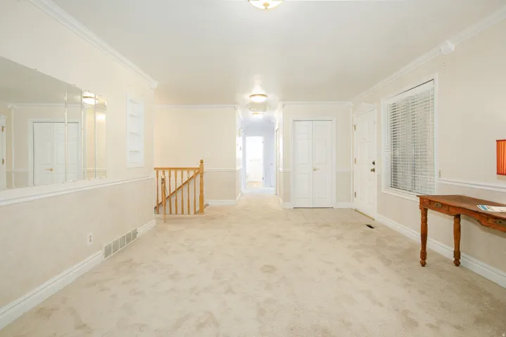 Inviting entry featuring neutral-toned carpeting, white baseboards, and crown molding
