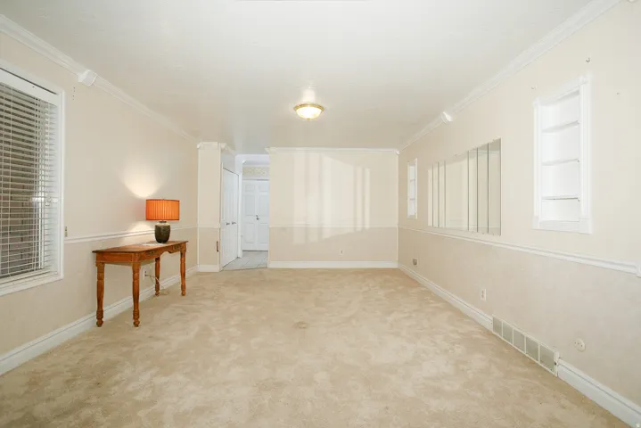 Spacious room featuring neutral carpet flooring and light-toned walls with chair rail molding
